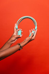 Close-up of woman hand holding eyeglasses against red background