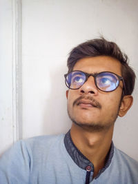 Portrait of young man wearing sunglasses against wall