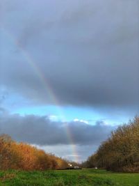 Scenic view of rainbow over field against sky