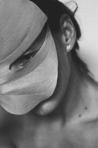 Close-up of woman covering face with leaf