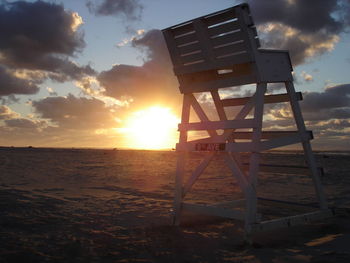 Lifeguard hut on beach against sky during sunset