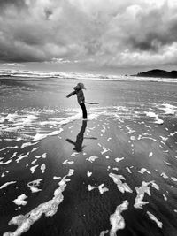 Full length of girl standing at beach against sky