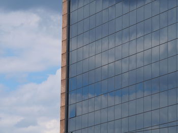 Low angle view of clouds reflecting on glass building