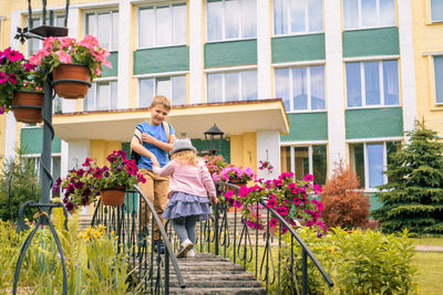 Woman walking by potted plants against building