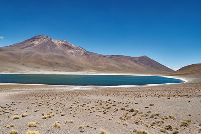 Scenic view of sea and mountains against clear blue sky