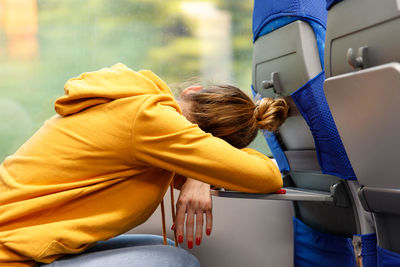 Side view of woman sleeping in train