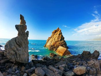 Rock formations on shore against blue sky