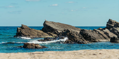 Rock formations on beach against sky