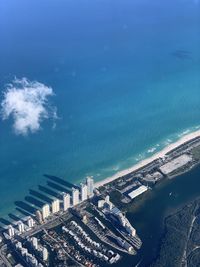 High angle view of buildings by sea against blue sky