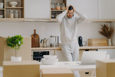 Man with head in hands standing at new home