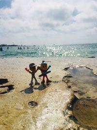 Children on beach against sky