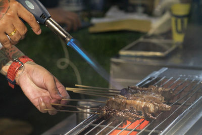 Close-up of man preparing food on barbecue grill