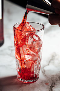 Cropped hand pouring drink on table