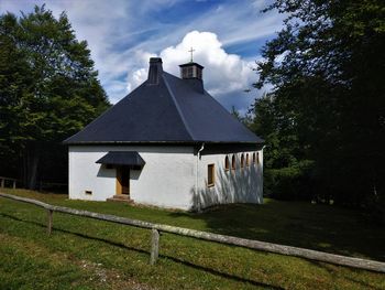 House amidst trees and buildings against sky