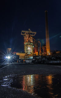 Illuminated factory against sky at night