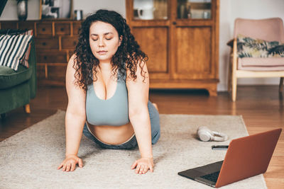 Portrait of young woman sitting on hardwood floor at home