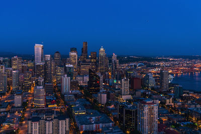 Illuminated buildings in city against blue sky