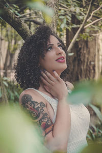 Thoughtful young woman with ganesha tattoo on arm