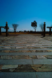 Surface level of footpath against clear blue sky