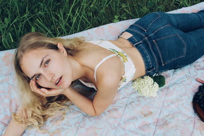 High angle portrait of woman lying on blanket at park