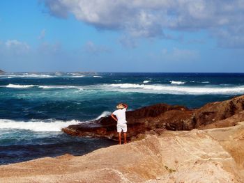 Woman standing on sea shore against sky