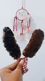 Close-up of hand holding ice cream over white background