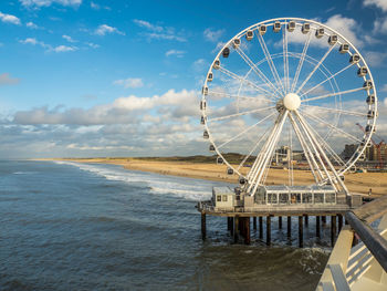 Ferris wheel by sea against sky