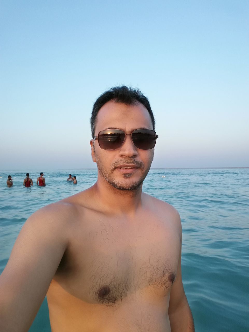 sea, horizon over water, water, young adult, clear sky, vacations, summer, young men, front view, beach, shirtless, smiling, headshot, leisure activity, lifestyles, looking at camera, blue, person, tourist, scenics, waterfront, swimming, day, weekend activities, enjoyment, tranquil scene, human face, city life, nature