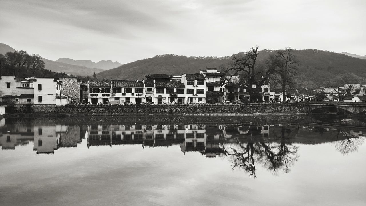 reflection, water, mountain, sky, built structure, waterfront, mountain range, nature, architecture, outdoors, day, lake, cloud - sky, building exterior, no people, tree, beauty in nature, animal themes, mammal