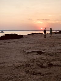 Silhouette people on beach against sky during sunset