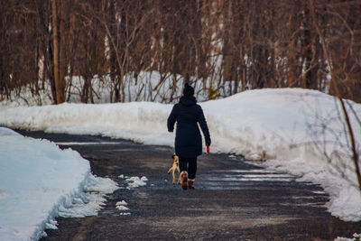 Rear view of woman walking on snow covered land