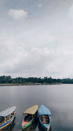 Boats moored in lake against sky