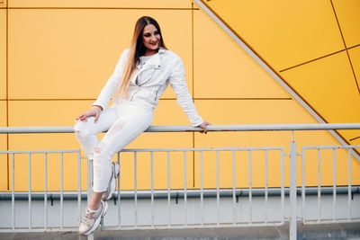 Portrait of young woman standing against railing