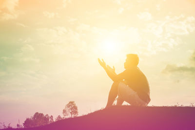 Side view of silhouette man holding umbrella against sky during sunset