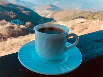 Close-up of coffee cup on table against mountains