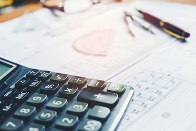 High angle view of calculator with blueprints on table