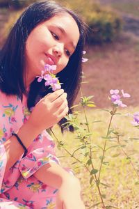 Teenage girl smelling pink flowers on field