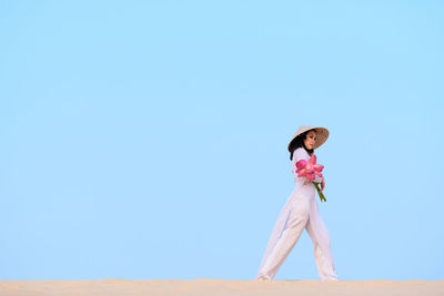Full length of woman standing against clear blue sky