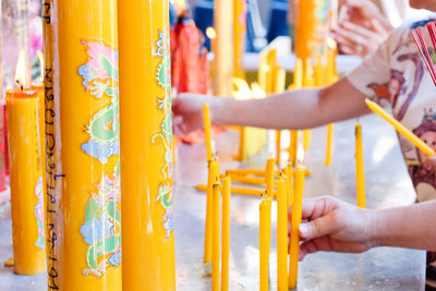 Cropped hands holding yellow candles at temple