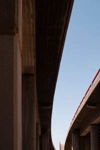 Low angle view of bridge and buildings against clear sky