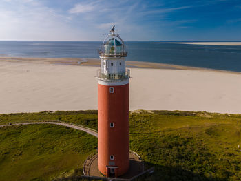 Lighthouse by sea against sky