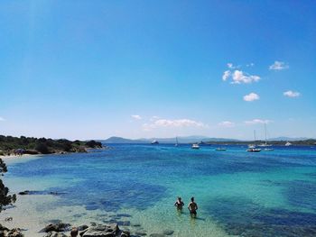 People on beach against clear blue sky