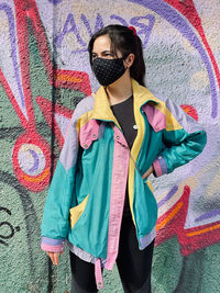 Midsection of man wearing sunglasses standing against graffiti wall