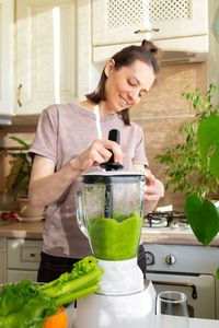 Woman making juice at kitchen