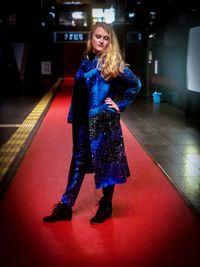 Full length of woman standing against wall at night