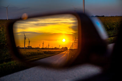 Road amidst field against sky during sunset