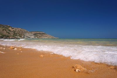 Scenic view of beach against clear blue sky