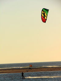 People on beach against clear sky during sunset