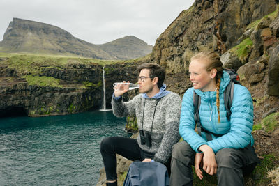 Friends sitting on water at mountain