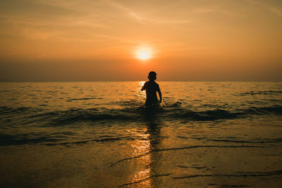 Silhouette woman on beach against sky during sunset